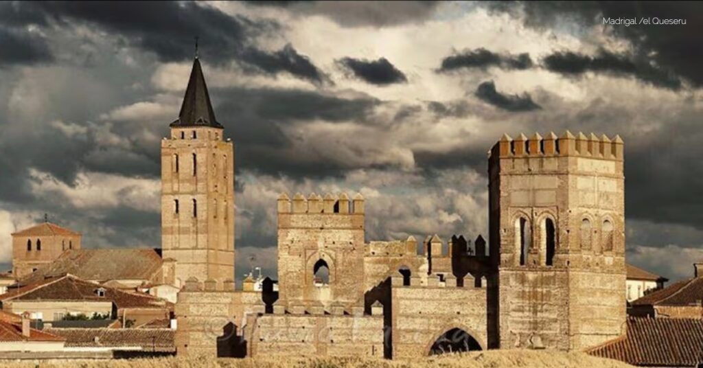 Stone medieval fortress with tall towers and crenellated walls under a moody, cloudy sky.